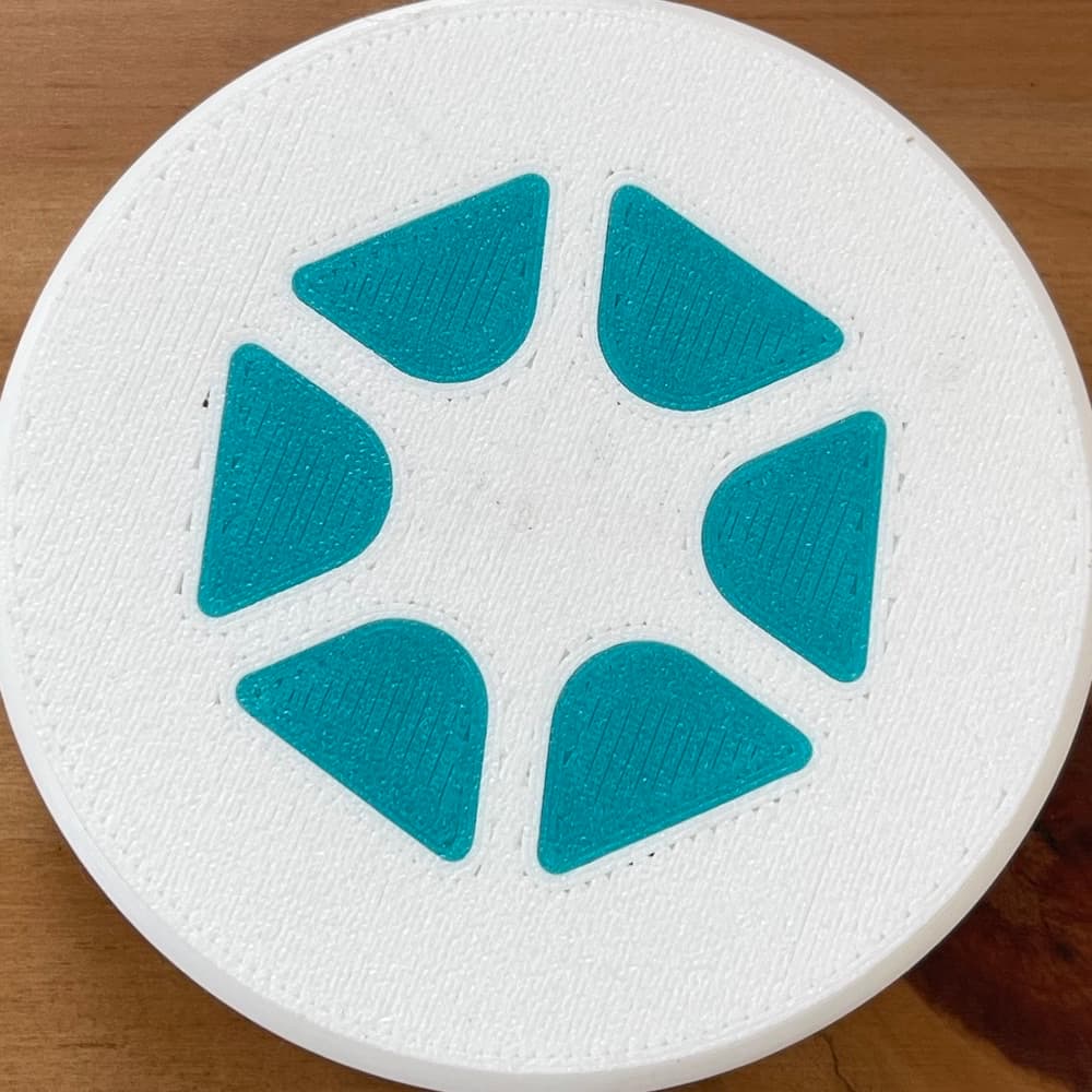 The Touchstone — a white disc with the teal aperture mark on its face